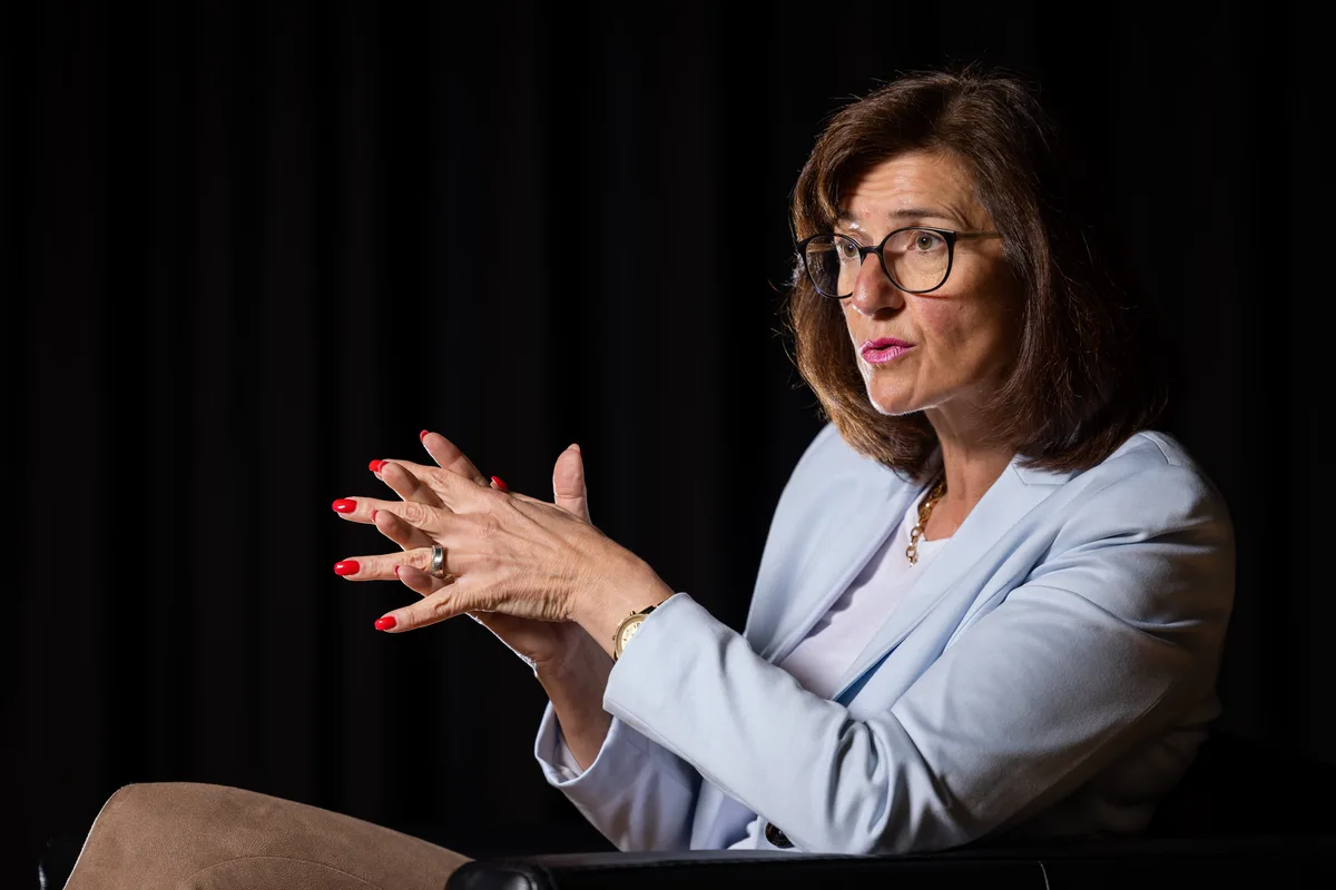 Eine Frau im Business-Look argumentiert an einer Podiumsdiskussion.